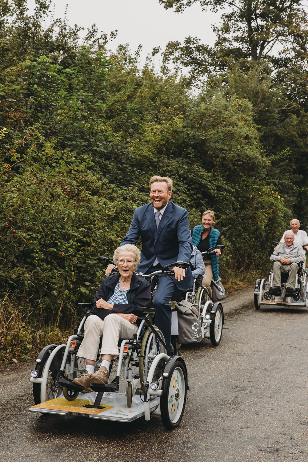 De Koning fietst met een Zonnebloemdeelnemer